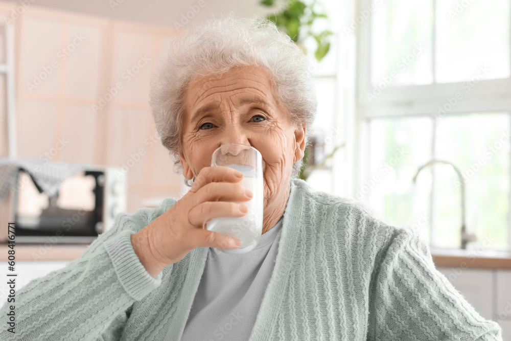 Senior woman drinking milk in kitchen, closeup