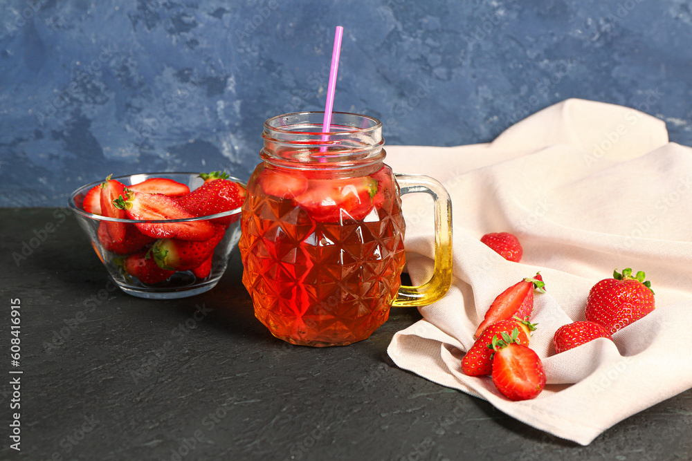 Mason jar of juice and bowl with strawberry on black table