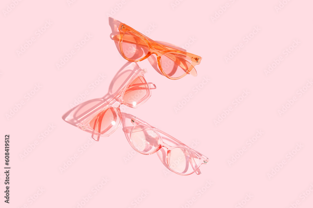 Different stylish sunglasses on pink background