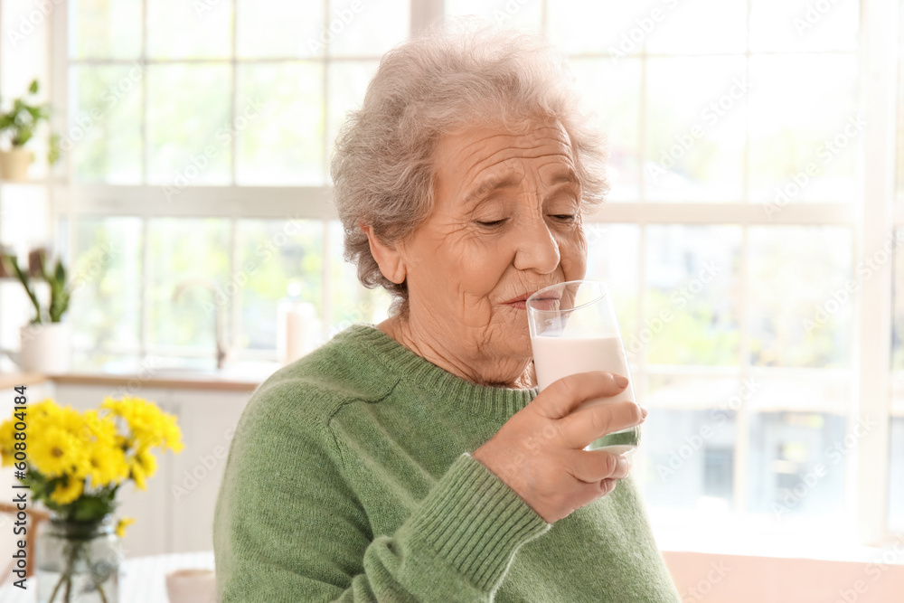 Senior woman drinking milk in kitchen, closeup