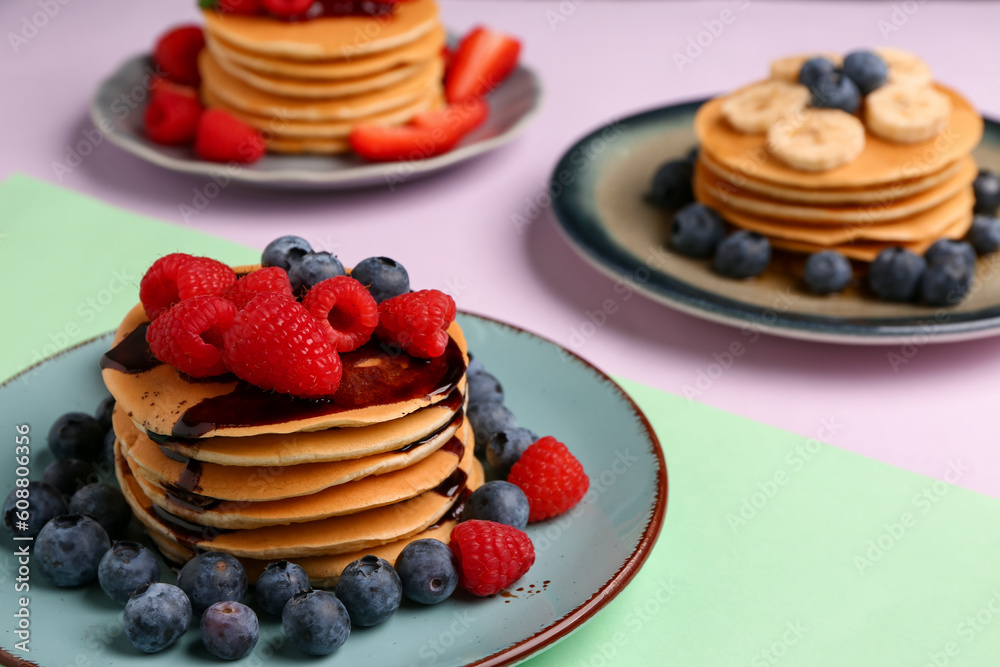 Plates with sweet pancakes and berries on color background, closeup