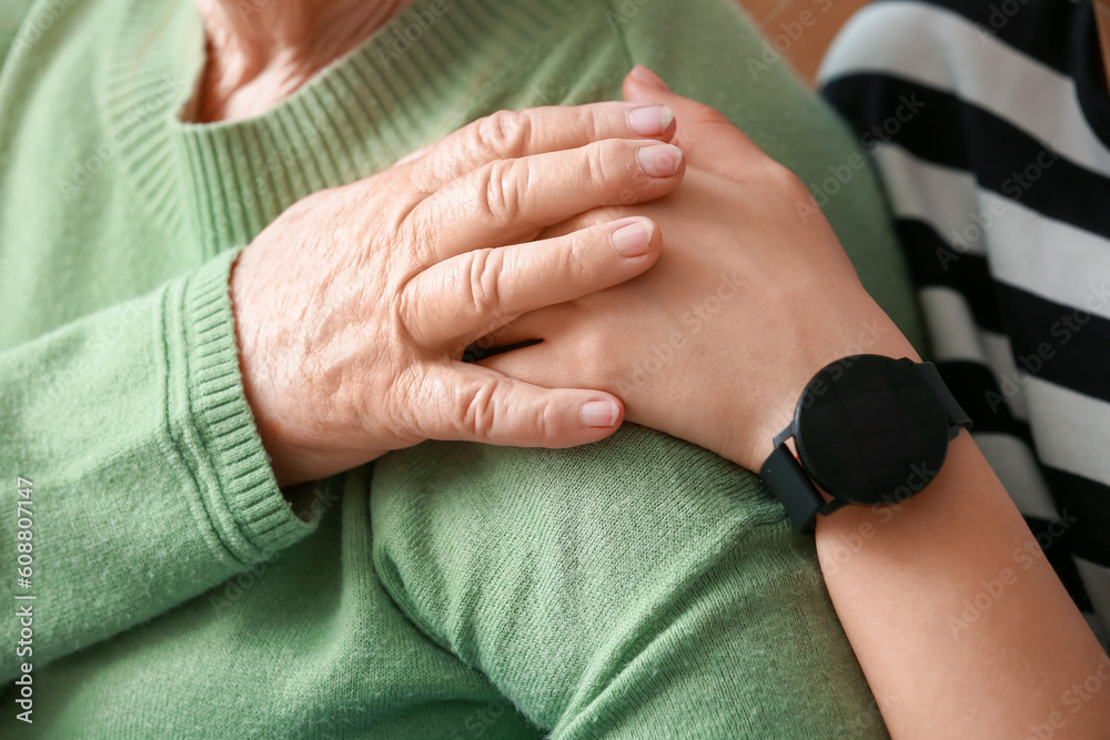 Young woman with her grandmother hugging at home, closeup