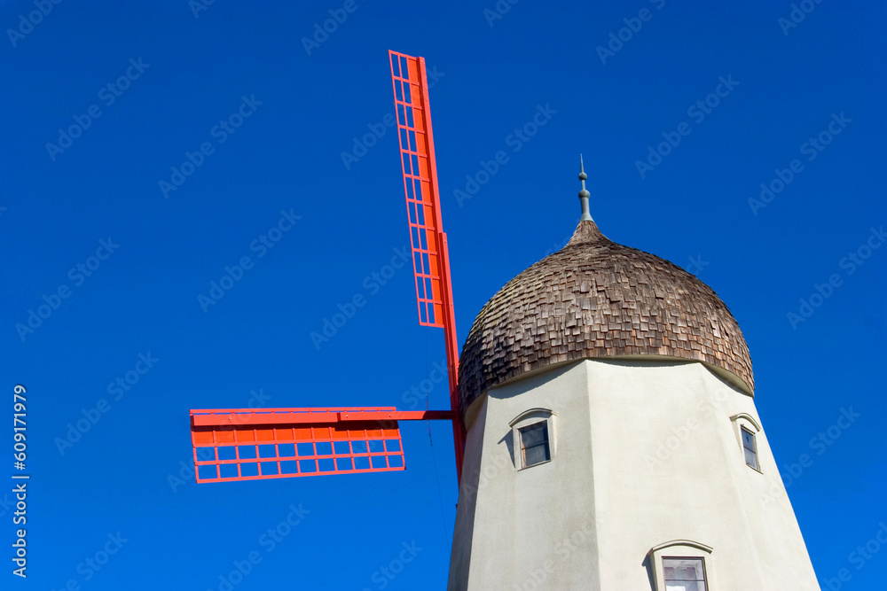 Tall windmill building sits in front of a clear blue sky.