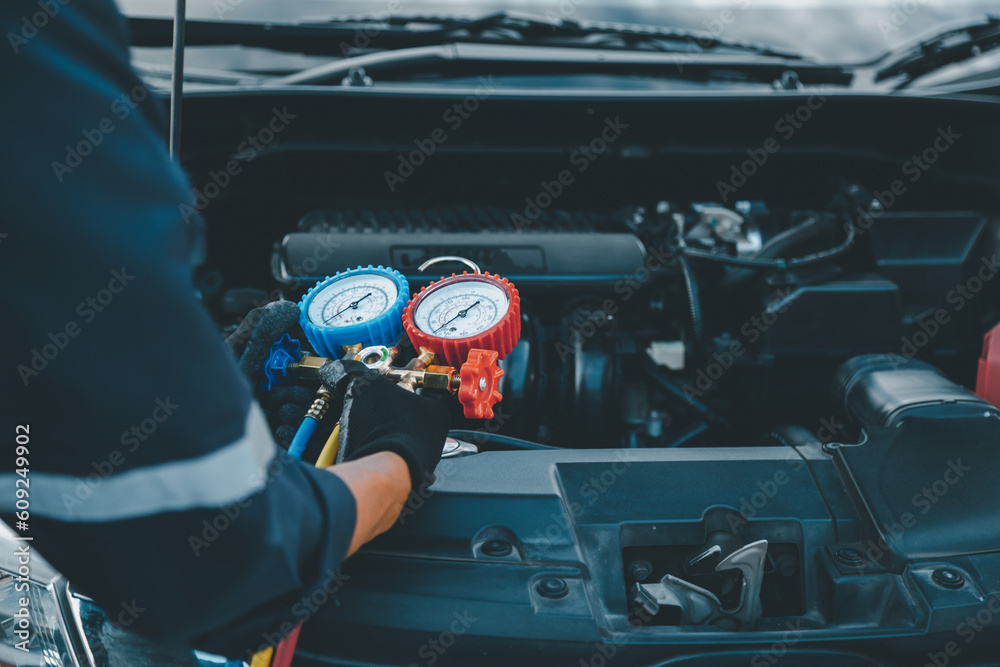 Close up hand of auto mechanic using measuring manifold gauge check the refrigerant and filling car 