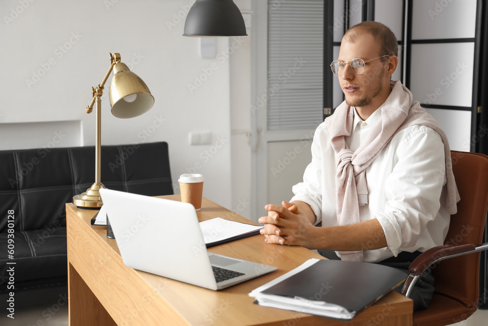 Male tutor with laptop giving online lesson at home