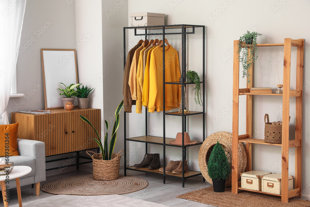 Interior of light living room with shelving unit and clothes