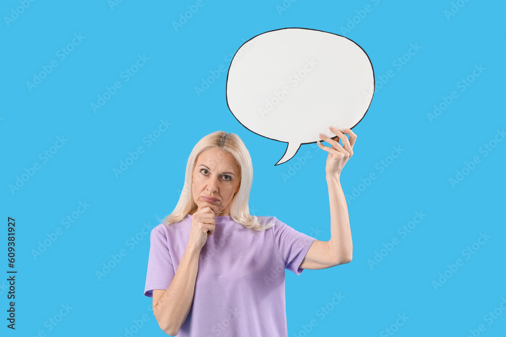 Thoughtful mature woman with blank speech bubble on blue background