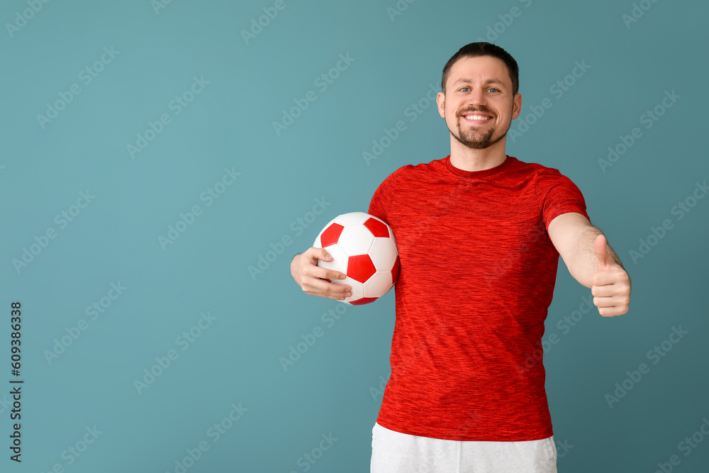 Happy man with soccer ball showing thumb-up on blue background