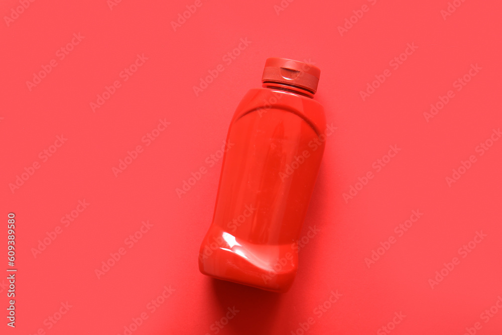 Bottle of ketchup on red background