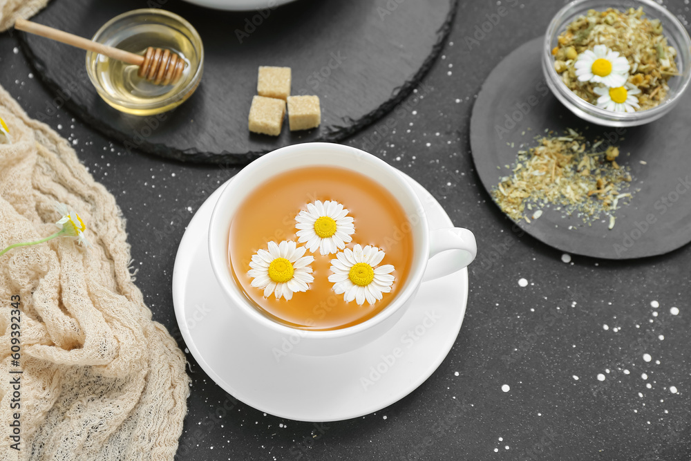 Cup of hot chamomile tea on dark background