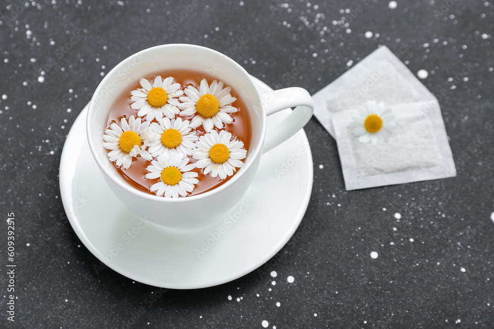 Cup of hot chamomile tea on dark background