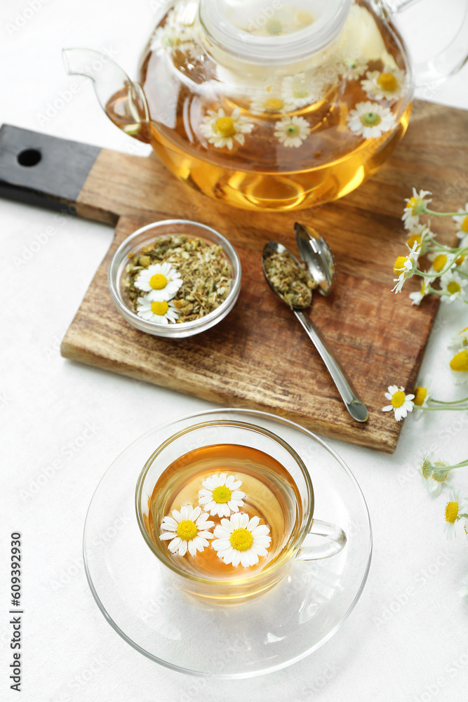 Cup of hot chamomile tea on light background