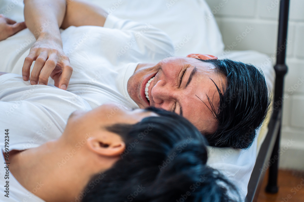 Asian new marriage couple lying down on bed and looking at each other. 