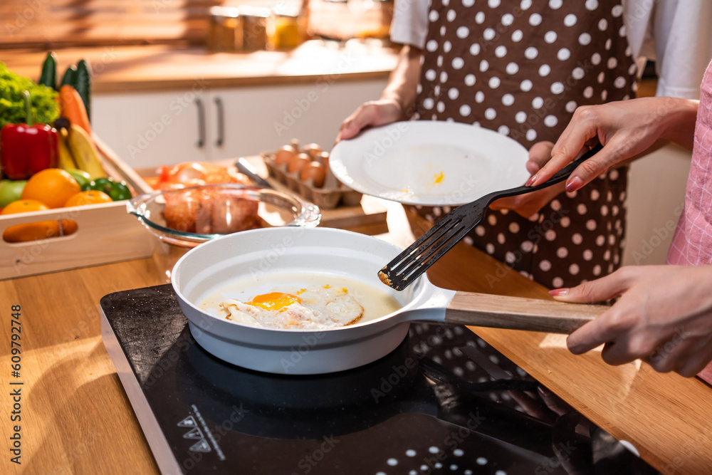 Close up hands of young couple fried eggs on a pan in kitchen at home. 