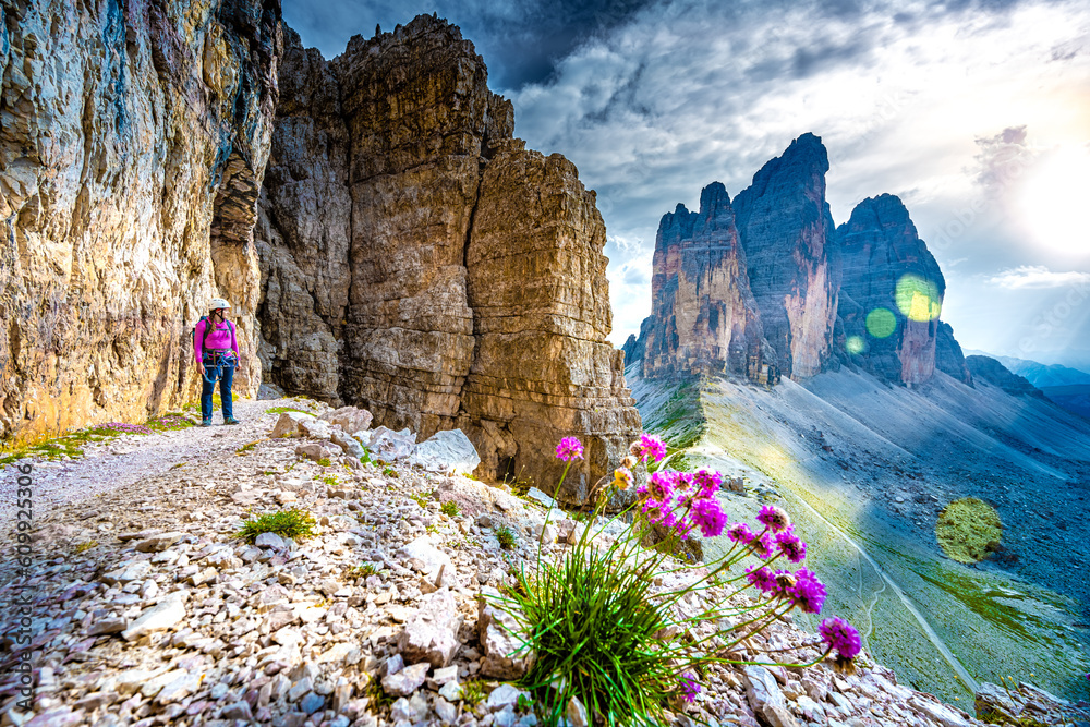 Young athletic woman enjoys scenic view on Tre Cime from via ferrata in the evening. Tre Cime, Dolom