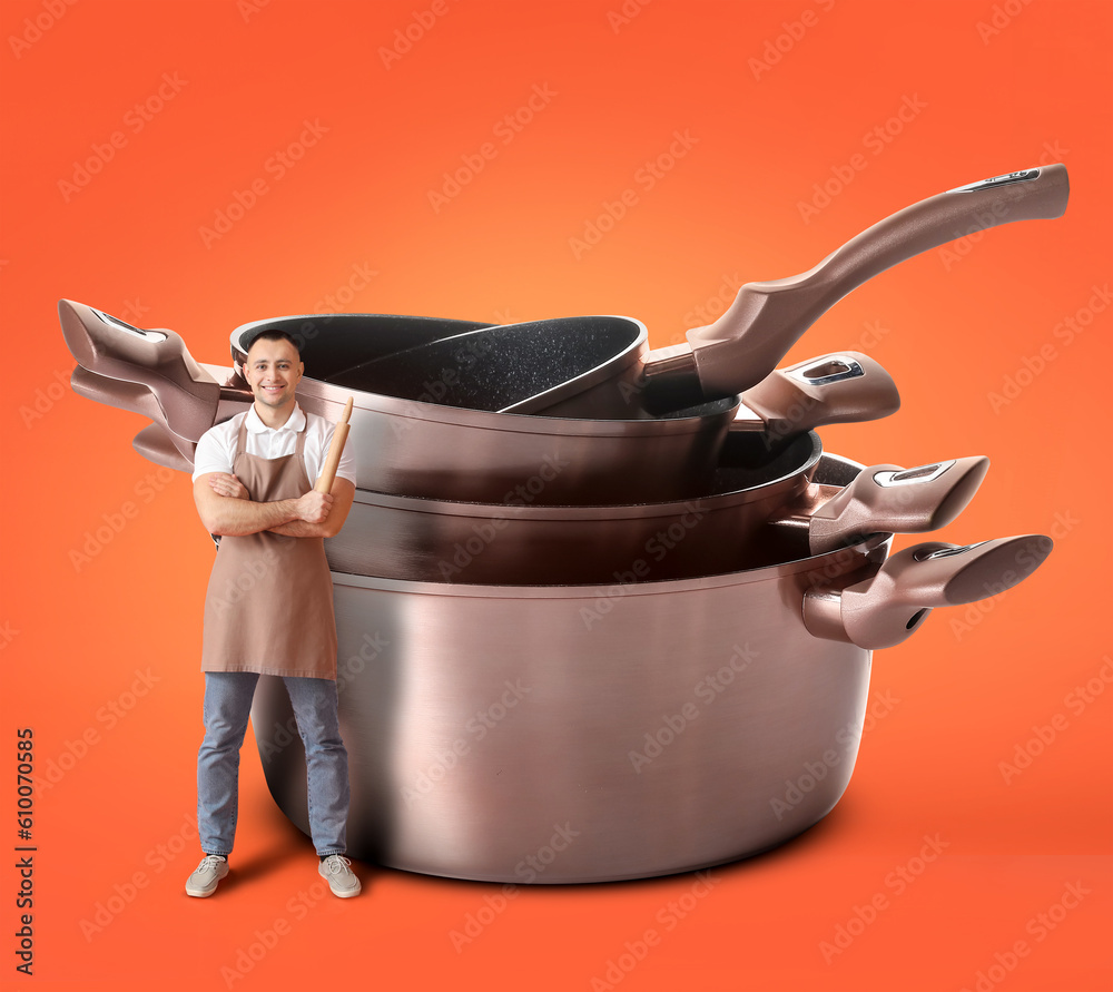 Handsome man with rolling pin and set of big cooking pots on orange background