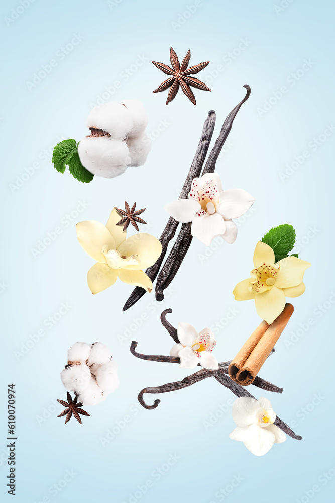 Flying vanilla sticks, orchid flowers and spices on light blue background