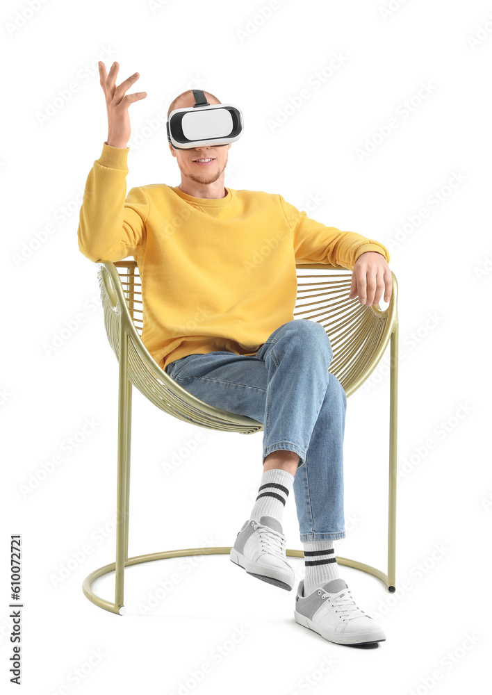 Handsome man with VR glasses sitting in golden armchair on white background