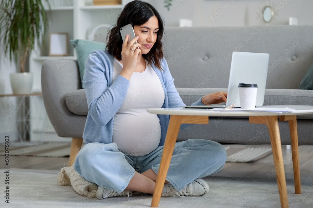 Working pregnant woman talking by mobile phone at home