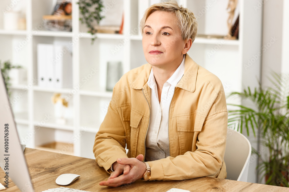 Thoughtful mature woman sitting at table in office