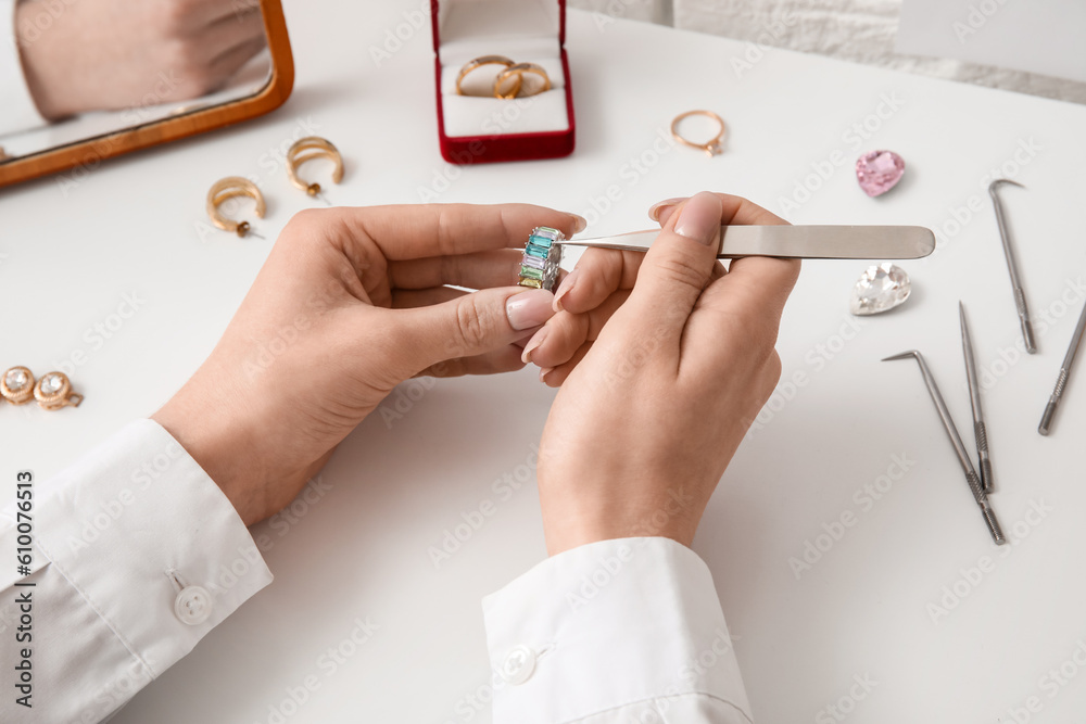 Female jeweler making ring on white table, closeup