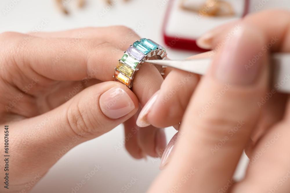 Female jeweler making ring on white table, closeup