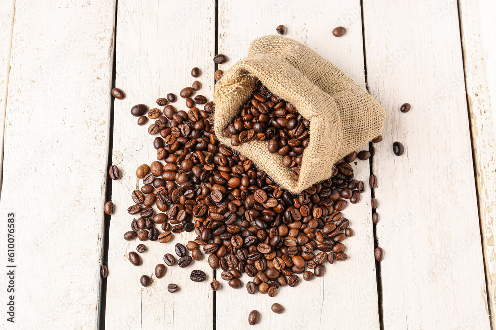 Bag with coffee beans on light wooden background