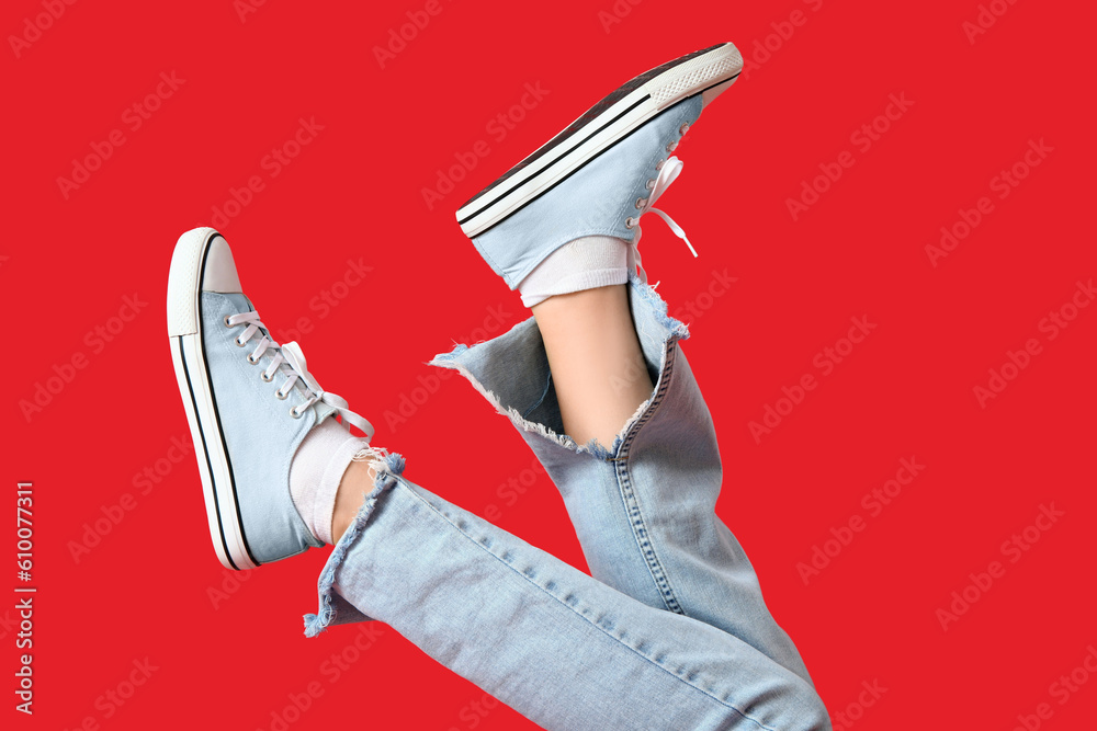 Female legs in stylish gumshoes on red background, closeup