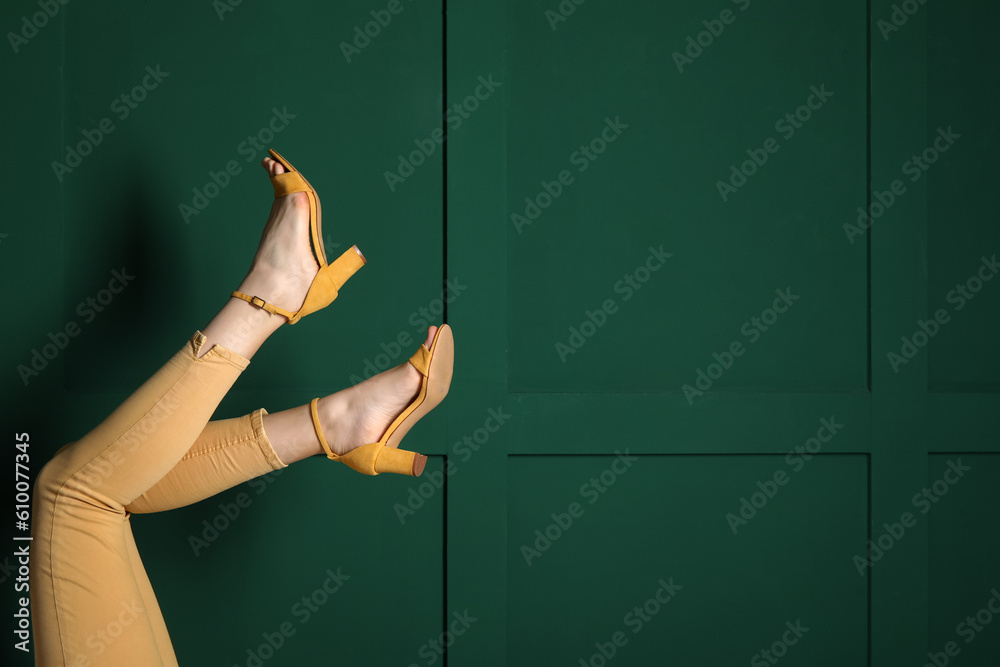 Female legs in stylish shoes against color wall