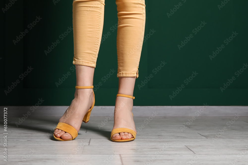 Female legs in stylish shoes against color wall