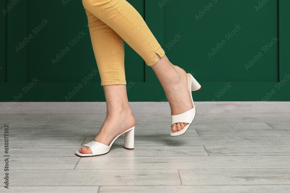 Woman in stylish summer shoes against color wall, closeup