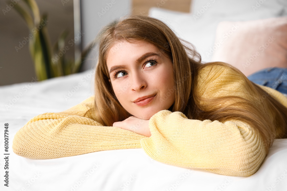 Dreaming young woman lying on bed at home, closeup