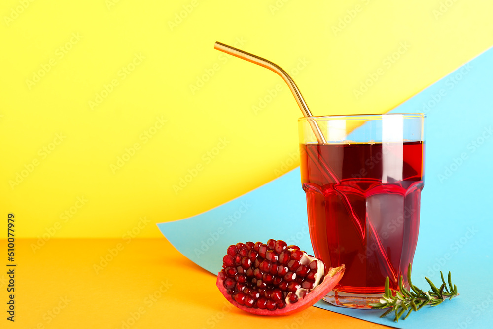 Glass of fresh pomegranate juice on colorful background