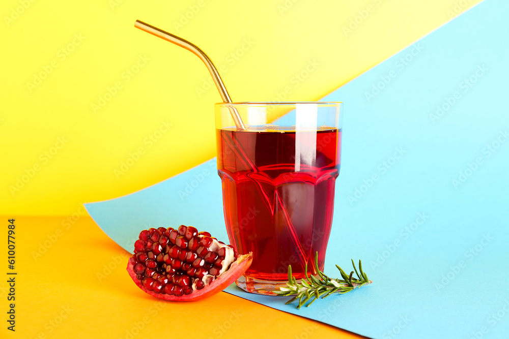 Glass of fresh pomegranate juice on colorful background