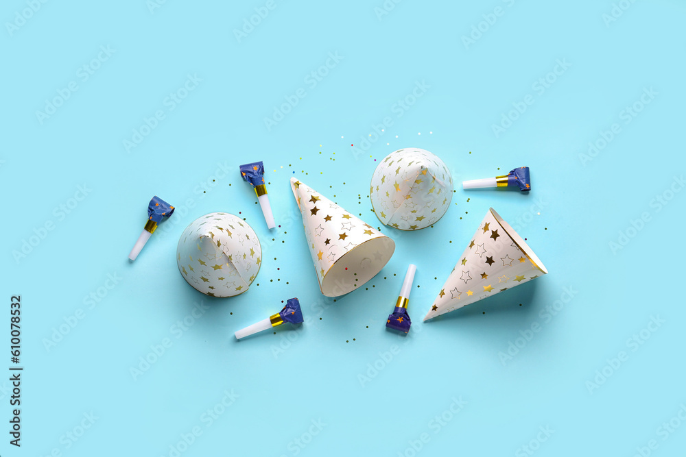 Composition with party hats and whistles on pale blue background