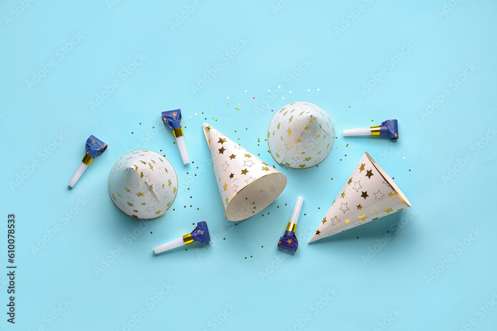 Composition with party hats and whistles on pale blue background