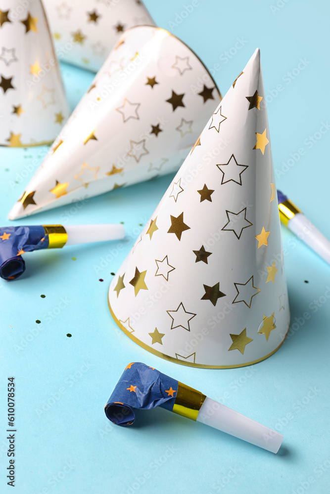 Composition with party hats and whistles on pale blue background