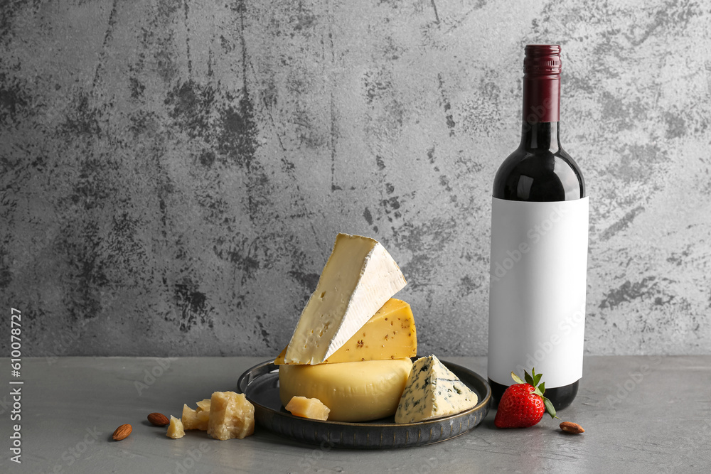 Different types of tasty cheese and bottle with wine on table