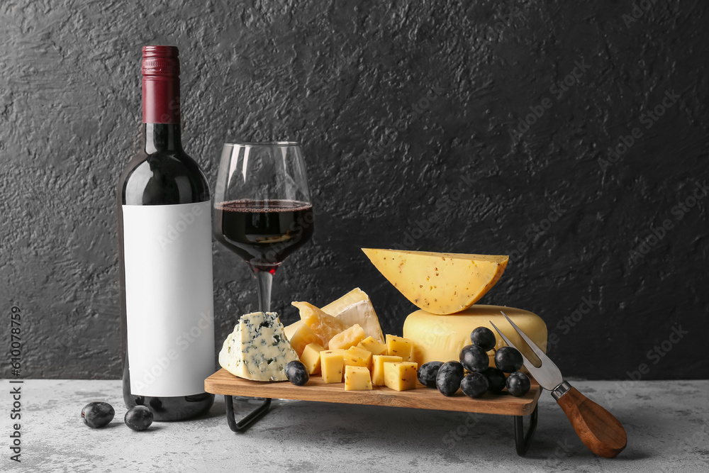 Different tasty cheese, glass and bottle with wine on table