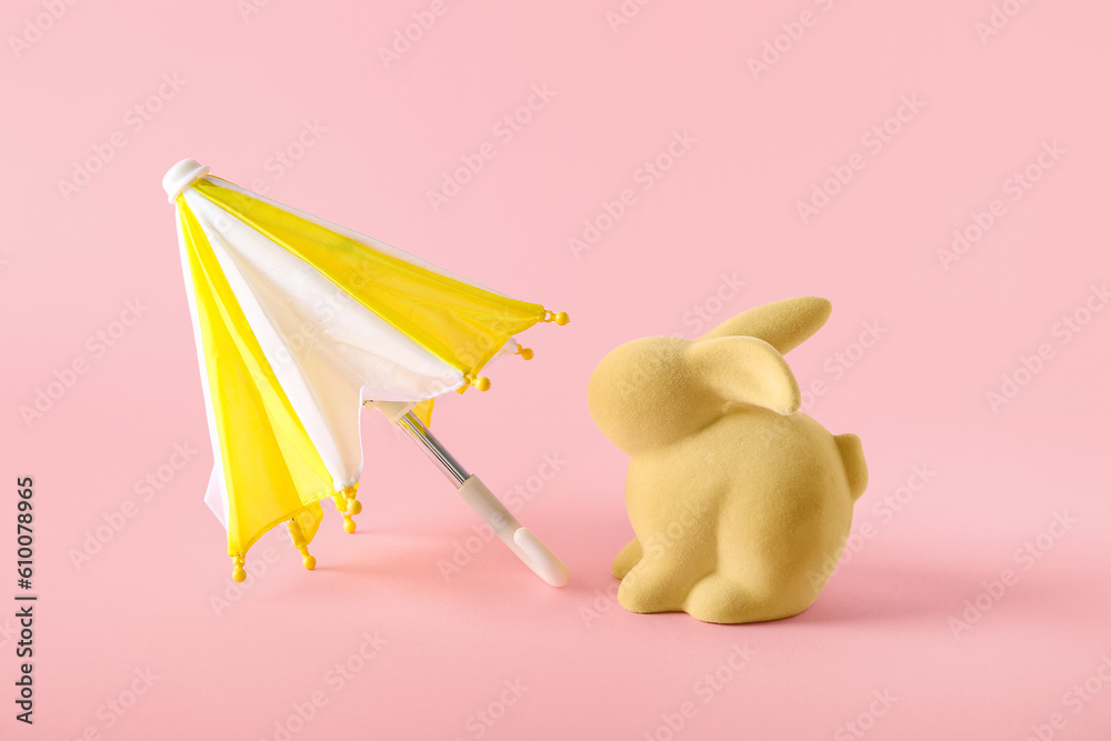 Creative composition with rabbit toy and mini umbrella on pink background