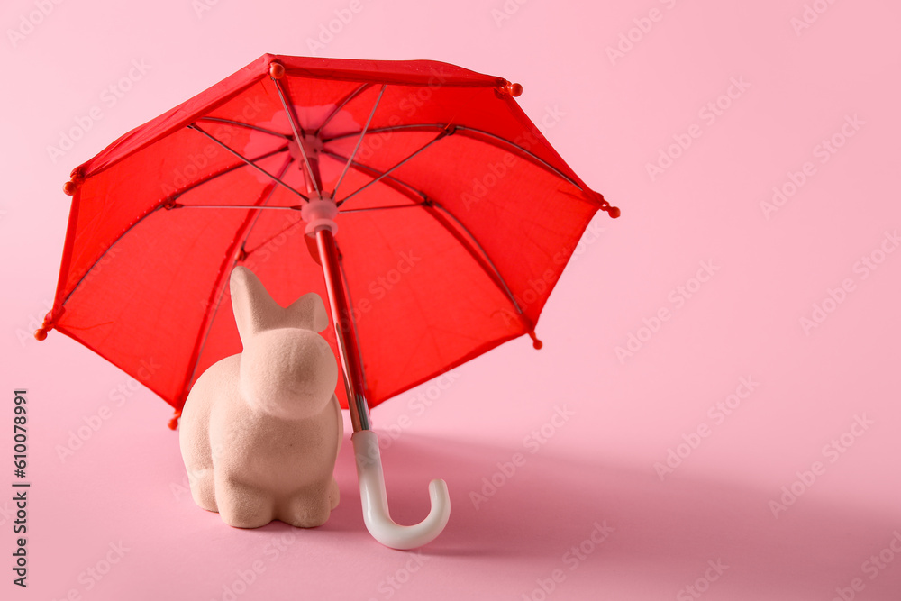 Creative composition with rabbit toy and red mini umbrella on pink background