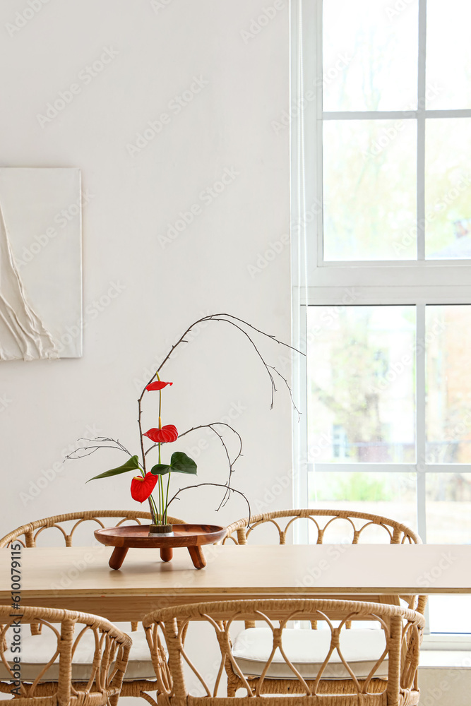 Dining table with beautiful ikebana in interior of room