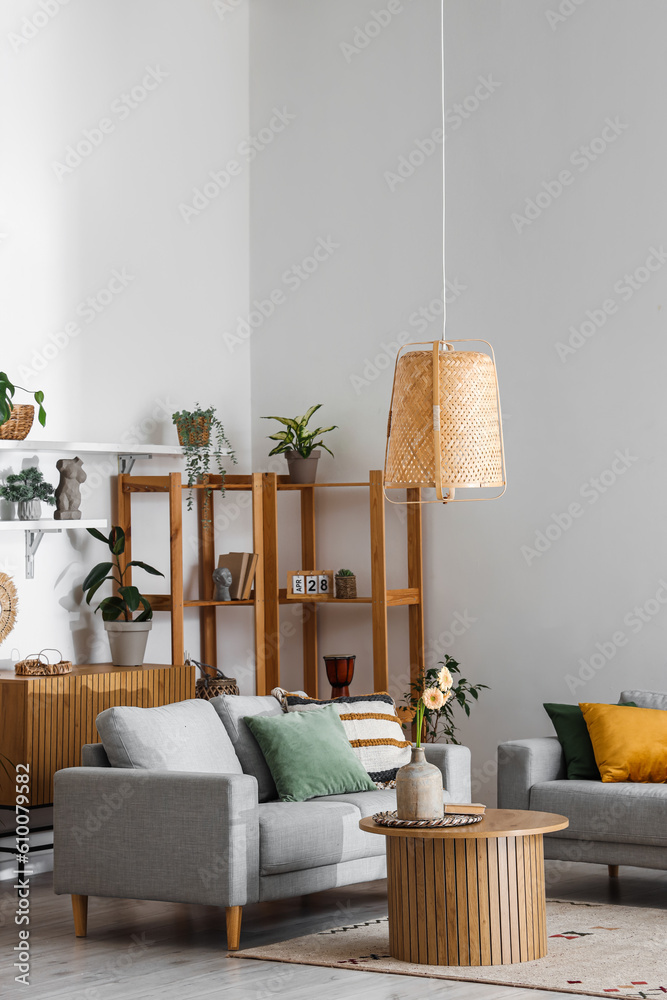 Interior of light living room with grey sofas and gerbera flowers on coffee table