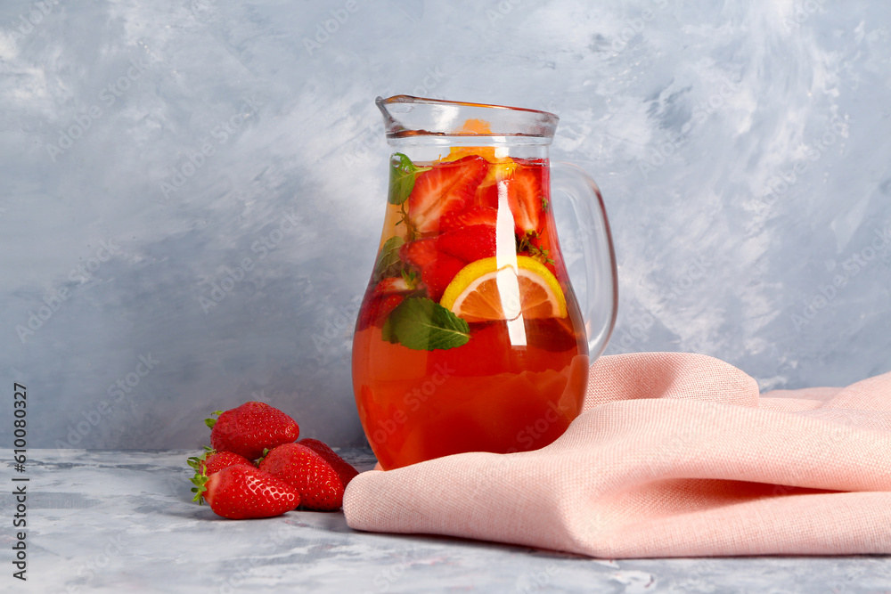 Jug of tasty strawberry juice on blue table