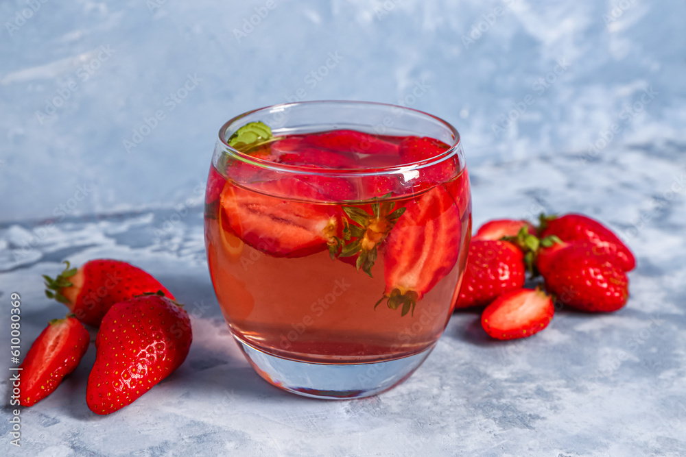 Glass of tasty strawberry juice on blue table