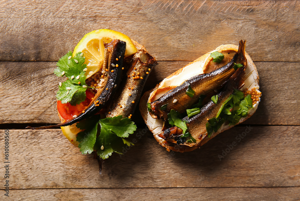 Tasty sandwiches with canned smoked sprats on wooden background