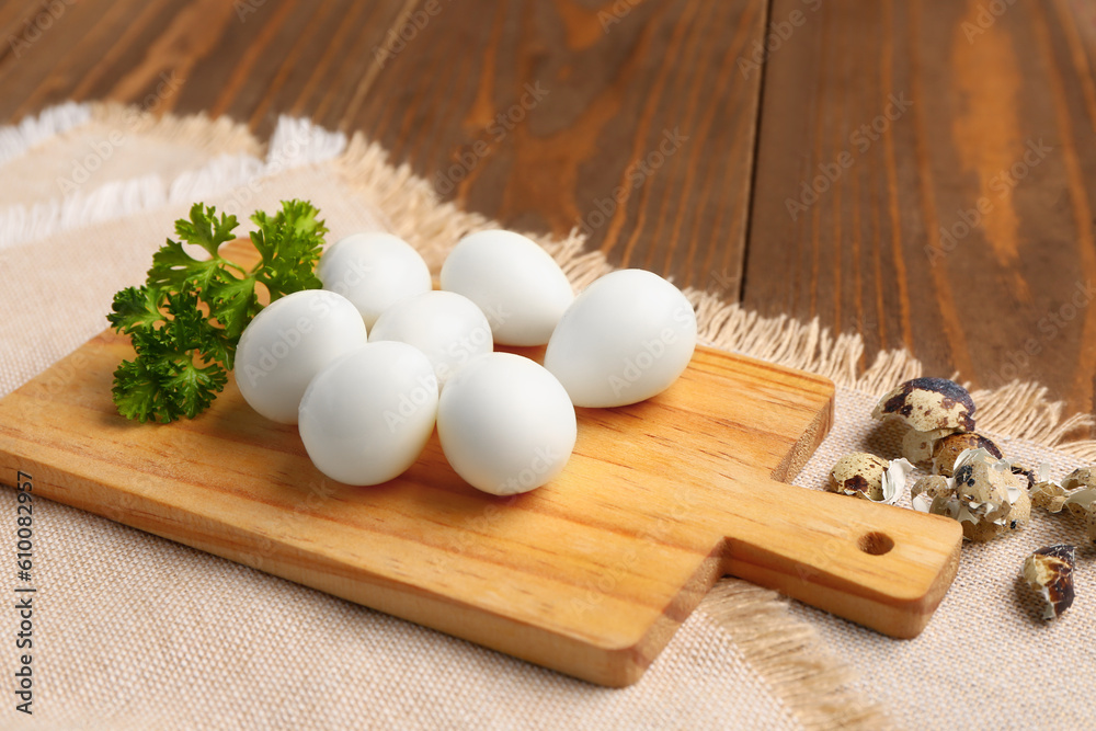 Board of boiled quail eggs with shells on wooden background