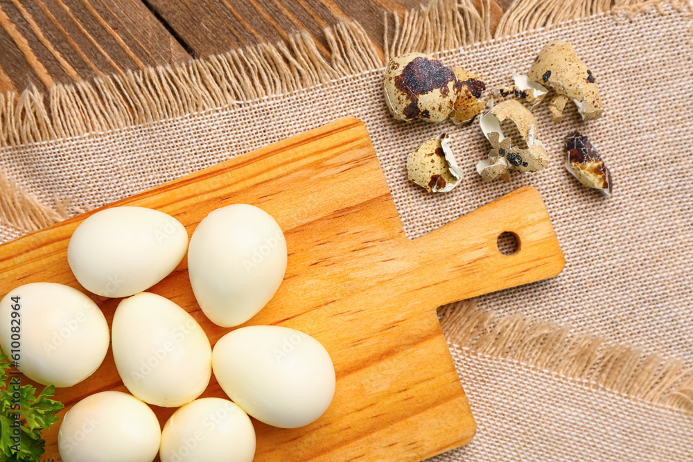 Board of boiled quail eggs with shells on wooden background