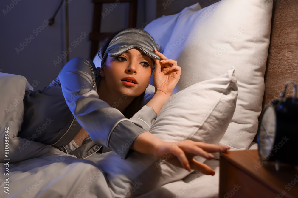 Young woman watching time in bedroom at night