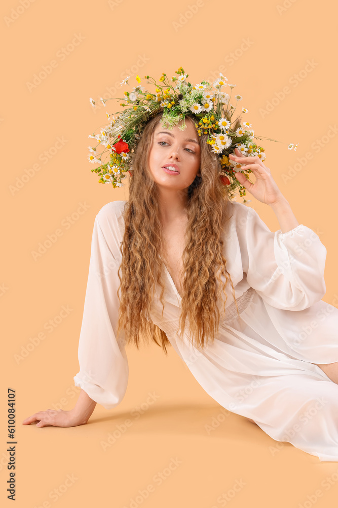 Beautiful young woman in flower wreath on beige background. Summer solstice